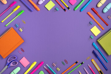Frame of colorful school and office stationery set on violet background. Flatly, copyspace.