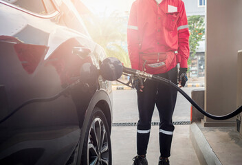 Filling gasoline into a car at a gas station. Fuel pump plugs into a car.