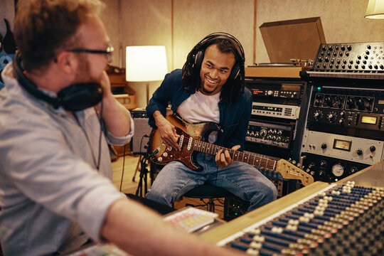 Smiling guitarist and producer working in a recording studio
