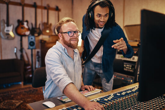 Producer and musician collaborating together in a recording studio