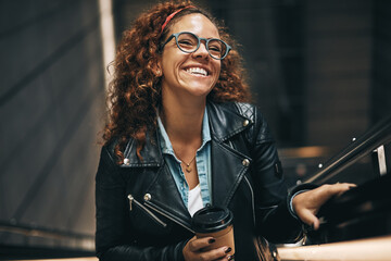 Stylish woman drinking coffee on a metro station escalator