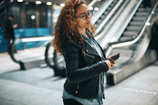 Young woman listening to music on a metro station platform