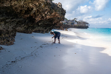 Woman looks for seashells on the beach in Zanzibar, Tanzania