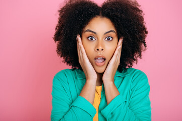 Amazed shocked african american or brazilian curly haired beautiful young woman in green shirt, looking at camera in surprise, holding palms near cheeks and opening her mouth, isolated Generative AI - obrazy, fototapety, plakaty