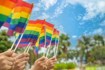 Fototapeta premium diversity people hands raising colorful lgbtq rainbow flags together , a symbol for the LGBT community