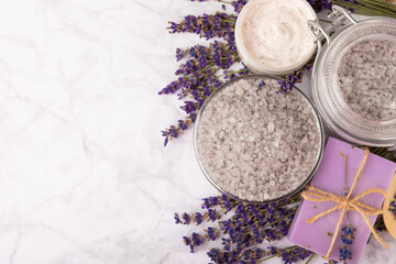 Fototapeta na wymiar Lavender spa.Sea salt,lavender flowers,aroma candle,body cream and handmade soap.Natural herbal cosmetics with lavender flowers on marble background.Relax concept.Beauty treatments.Copy space.