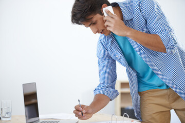 Fototapeta premium Checking his schedule. a handsome young man talking on his cellphone while in the office.