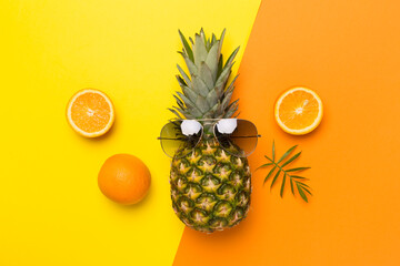 Creative pineapple hipster in sunglasses on color background, top view