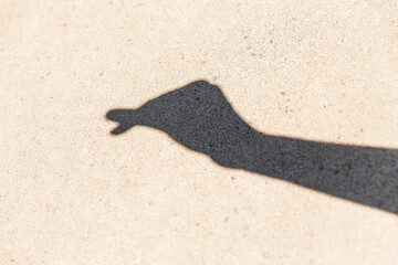 gesture, shadow play and silhouette concept - close up of hand showing korean heart gesture on concrete background