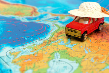 toy car in a straw hat on the physical map of the world, travel content