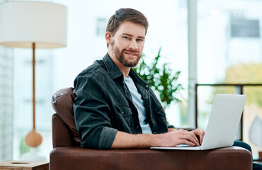 Fototapeta premium Its not lockdown without unlimited wifi. a young man using a laptop on the sofa at home.