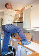 Kitchen Fitters: Up to Measure. A fitter taking measurements and adding finishing touches to a new...