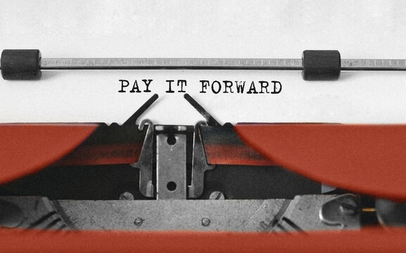 Text PAY IT FORWARD typed on retro typewriter