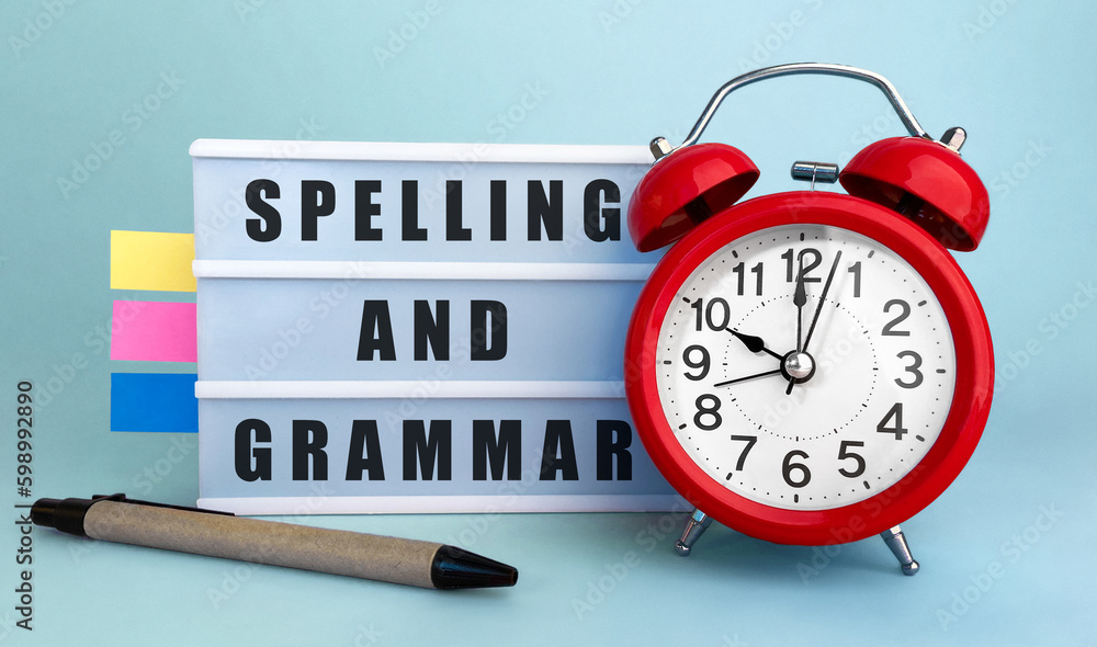 Poster text spelling and grammar written on the lightbox with alarm clock and colorfull stickers on blue ba
