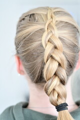 Back view of blond caucasian woman with braided hair. Blond highlights in long hair with beautiful hairstyle.