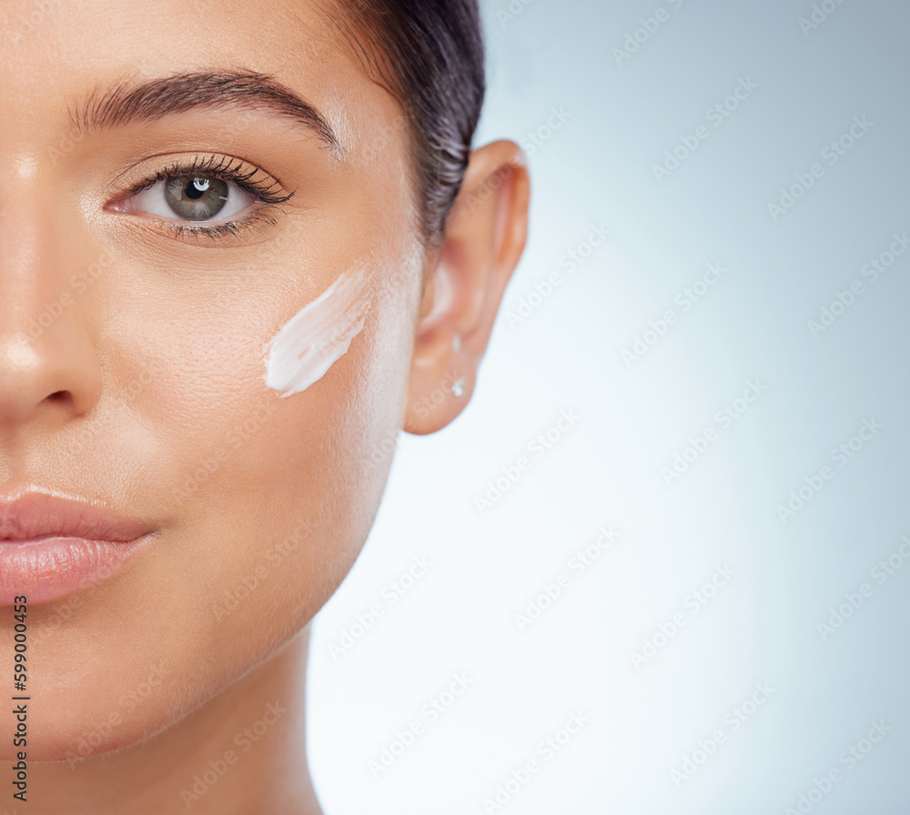 Poster Closeup portrait beautiful woman with face cream on her cheek posing with copyspace. Caucasian model isolated against grey studio background with product. Moisturise and sunscreen for healthy skincar