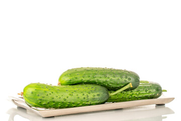 Three ripe green cucumbers on a metal tray, macro, isolated on white background.