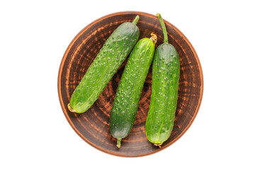 Three ripe green cucumbers on a clay plate, macro, isolated on white background, top view.