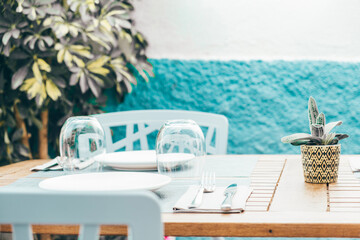 Wooden table set at outdoor terrace restaurant, cafe for summer dining on sunny day. Cozzy details...