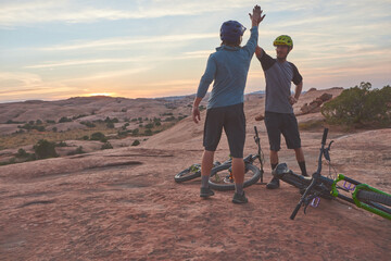 That was a good ride. two men giving each other a high five while out mountain biking. - obrazy, fototapety, plakaty