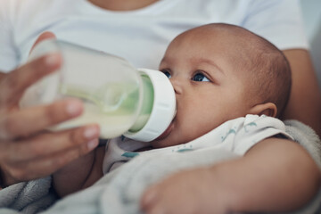 Breakfast, lunch and dinner all in a bottle. an adorable baby girl being bottle fed by her mother on the sofa at home.