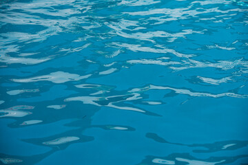 Ripple Water in swimming pool with sun reflection. Wavy water background.