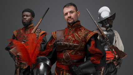 Shot of medieval three conquistadors with plumed helmets isolated on gray.