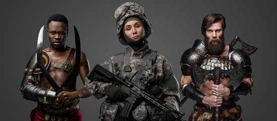 Shot of military woman with rifle and greek gladiator with scandinavian barbarian.