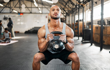 Fototapeta na wymiar Everyone has to start somewhere. a young man completing squats with a kettlebell.
