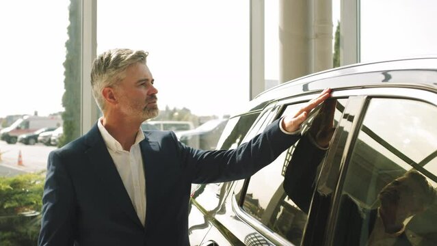 Male driver opening door while look the interior of his new auto. Man look the interior of his auto in a car dealership. Seriously beard grey hair man finally gets long-awaited car.