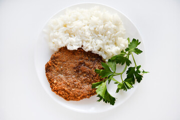 Two meat cutlets with rice on a white plate. Meat breakfast with rice porridge.