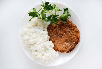 Two meat cutlets with rice on a white plate. Meat breakfast with rice porridge.