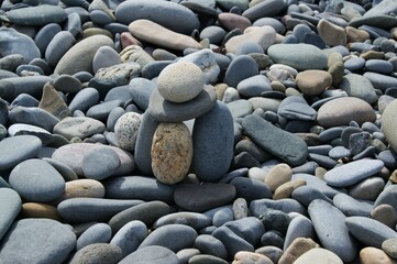 The tower is made of various pebbles on a stony beach.