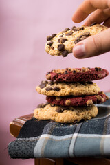 Hand taking chocolate cookie with chips on wooden table