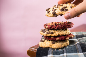 Hand taking chocolate cookie with chips on wooden table