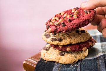 Hand taking red chocolate cookie with chips on wooden table