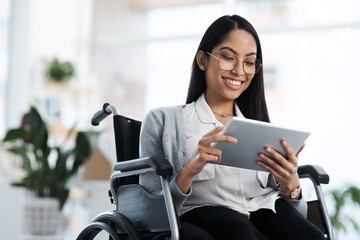 Happy and successful. an attractive young businesswoman in a wheelchair using her tablet in the office. - Powered by Adobe