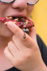 Girl bitting a red chocolate cookies with chocolate sauce 