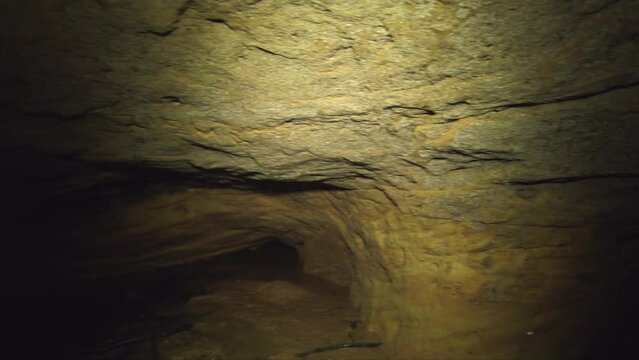 panning wide shot of the wall of an underground sandstone cave, river flows through it
