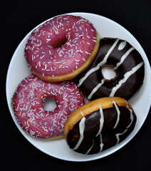 Delicious sweet donuts on a plate. Glazed doughnuts.