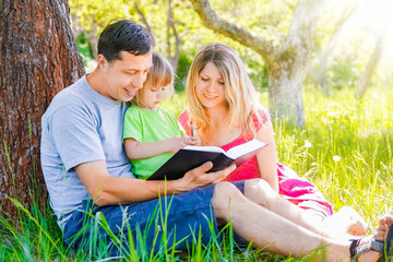 Happy family reading a book on the nature of the Bible