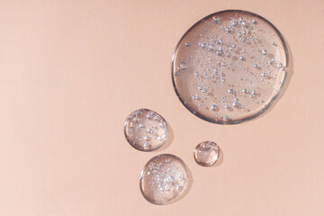 Drops and smears of cosmetics. Drops of liquid transparent gel with bubbles on a beige background.