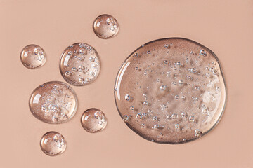 Drops and smears of cosmetics. Drops of liquid transparent gel with bubbles on a brown background.