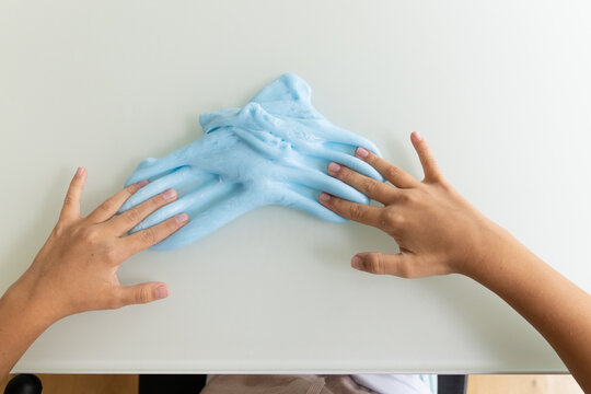 Child hands playing with blue slime 