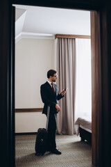 Fototapeta premium Back view of young elegant business traveler in formalwear entering comfortable hotel room in the morning