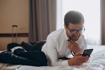 Young businessman working from a hotel room with his mobile phone.