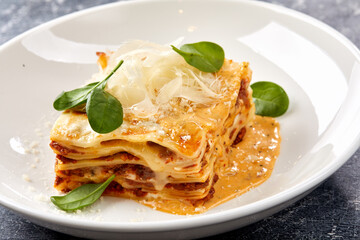 Traditional lasagna with bolognese sauce topped with basil leaves