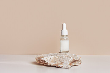 Fototapeta na wymiar Glass dropper bottle with extract coconut or serum on stand from natural stones on beige background. Natural Organic Spa Cosmetic concept, cosmetic product mock up, minimal style. Side view