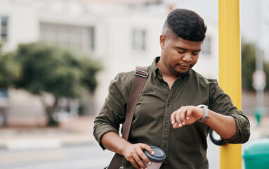 Dont make the mistake of being late. a young businessman checking the time while walking through the city.