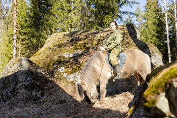 Icelandic horse and camouflaged woman in Finnish spring enviroment